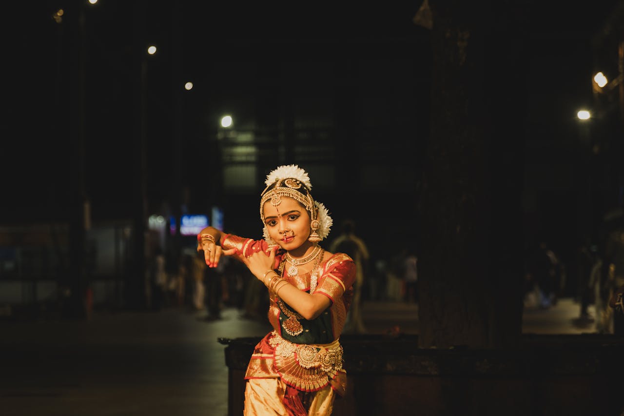 A Bharatanatyam dancer gracefully poses in traditional attire at night in Guruvayur, India.